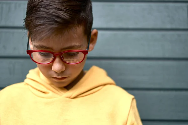 Niño con sudadera amarilla surfeando con su teléfono inteligente. Fondo rojo —  Fotos de Stock