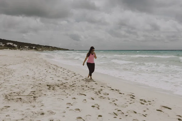 Klädd kvinna tar en promenad på stranden — Stockfoto