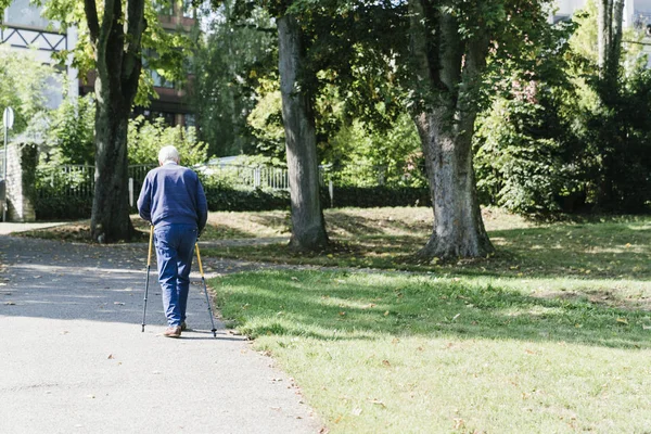 Older man walking with canes in the park
