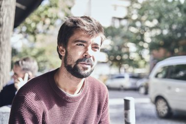 Kafede sigara içen çekici genç sakallı adam.