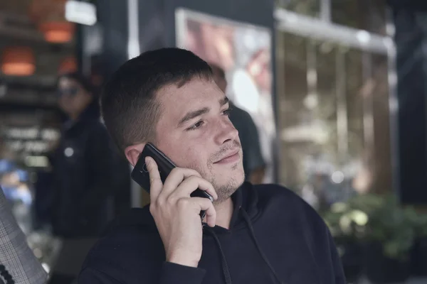 young man calling with his phone in a cafe terrace