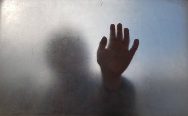 çocuğun el bulanık veya buzlu camın ardında karanlığa gömüldü