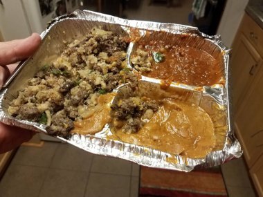 Mutfakta metal tepsisinde Etiyopya sığır eti ve bezelye ve fasulye tutan el