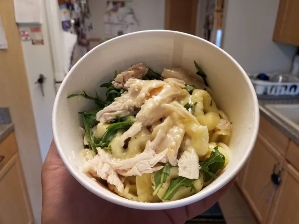 Palmo in mano di pollo e pasta e verdure in cucina — Foto Stock