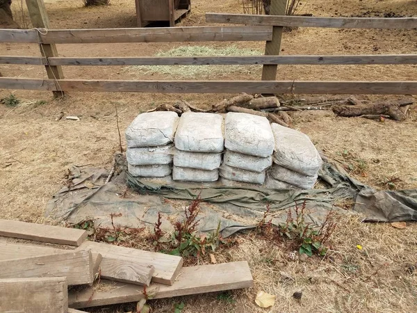Valla de madera y pilas de bolsas viejas de cemento — Foto de Stock