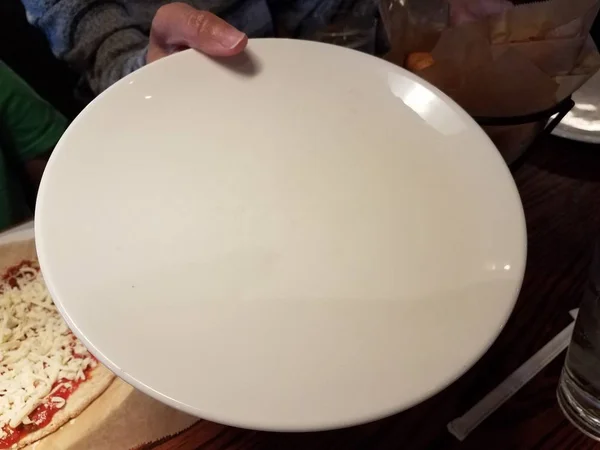 Γυναίκες χέρι κρατώντας ένα μεγάλο λευκό πιάτο — Φωτογραφία Αρχείου