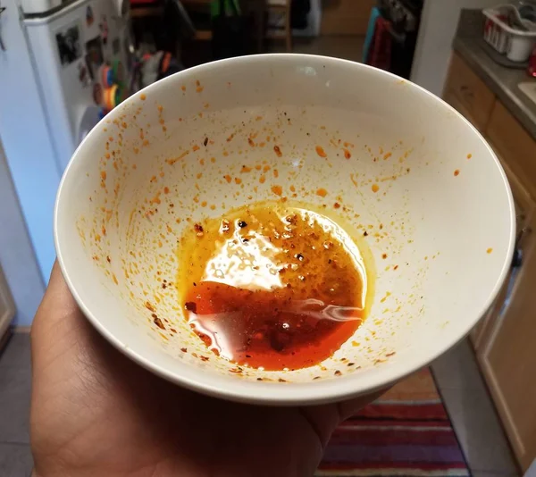 Hand Holding vit skål med röd olja i köket — Stockfoto