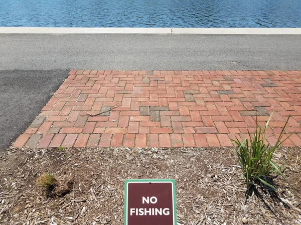Marrom sem sinal de pesca com tijolos vermelhos e água e asfalto — Fotografia de Stock