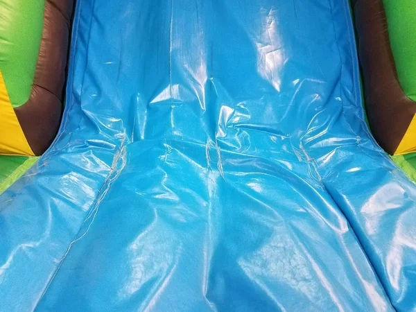 worn or weathered or damaged blue slide on bounce house