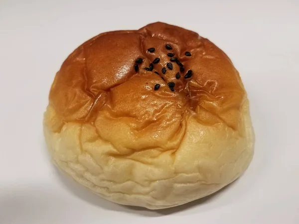Хлеб или булочка с черными семенами на белой поверхности — стоковое фото