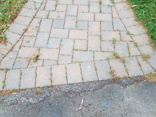 Szare kamienne płytki na ścieżce z niebieskimi znakami i asfaltem — Zdjęcie stockowe
