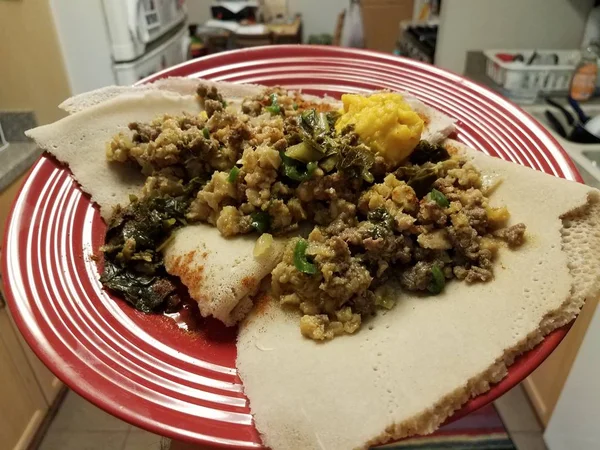 Äthiopisches Essen würzig Rindfleisch und Darm und Brot auf rotem Teller in der Küche — Stockfoto