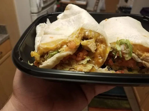 Mão segurando tortilla com frango e queijo na cozinha — Fotografia de Stock