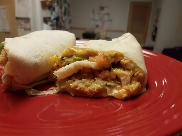 Hand hält Tortilla mit Huhn und Käse in der Küche auf rotem Teller — Stockfoto