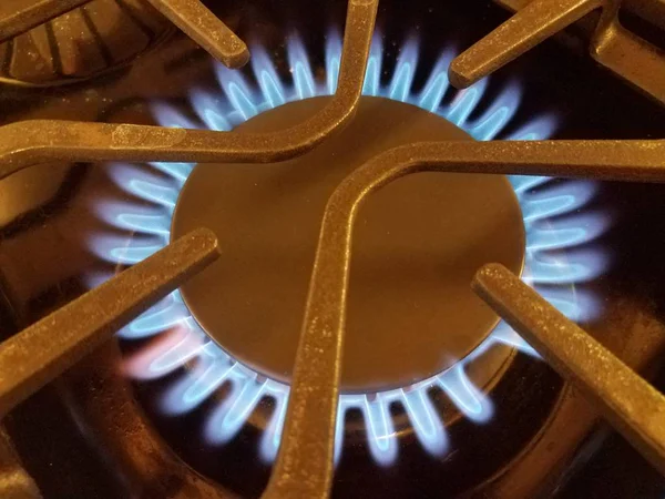 Blue flame on natural gas stove top with metal grate — Stock Photo, Image