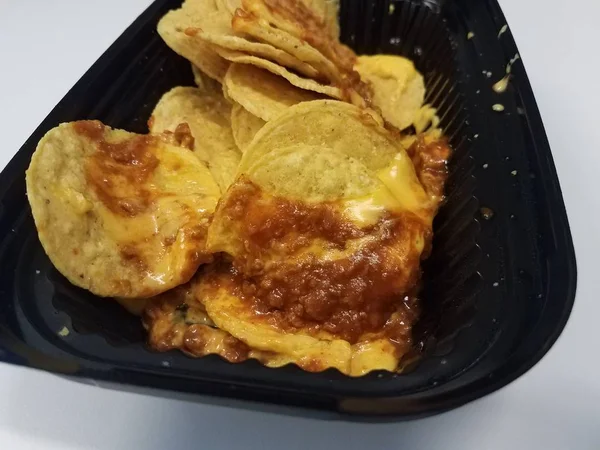 Tortilla chips met kaas en vlees saus in zwarte kunststof container — Stockfoto