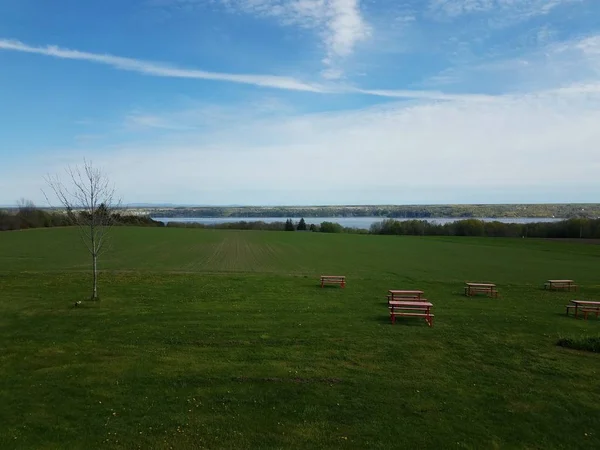 Röda picknick bord i grönt gräs eller fält med flod i Quebec, Kanada — Stockfoto