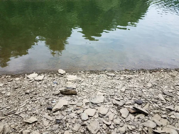 Rochas cinzentas quebradas e água na margem do rio ou lago — Fotografia de Stock