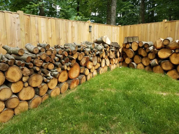 Skära trä staplade längs brunt trä staket — Stockfoto