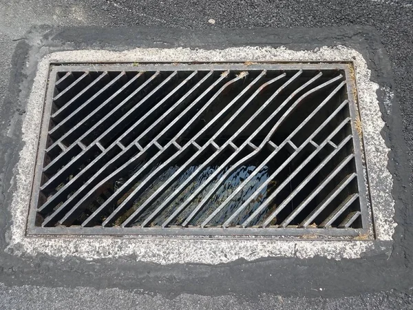 Black asphalt and metal drainage grate or bars — Stock Photo, Image