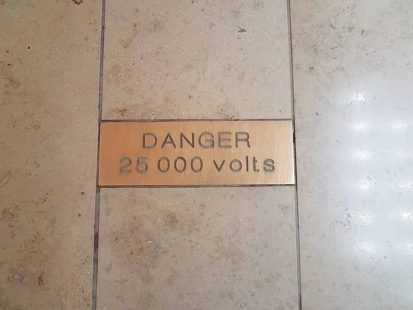 Gefahr 25000 Volt Warnschild auf Fliesenboden — Stockfoto