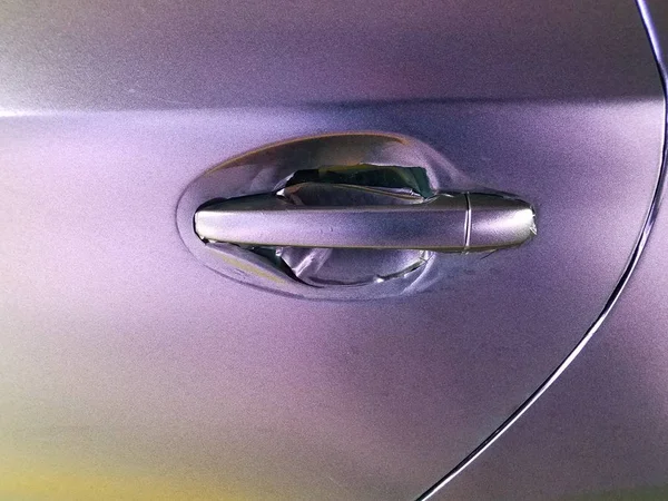 worn purple wrap on automobile with door handle