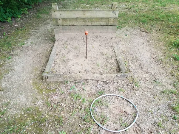 metal pole in horseshoe pit with wood backstop and plastic circle