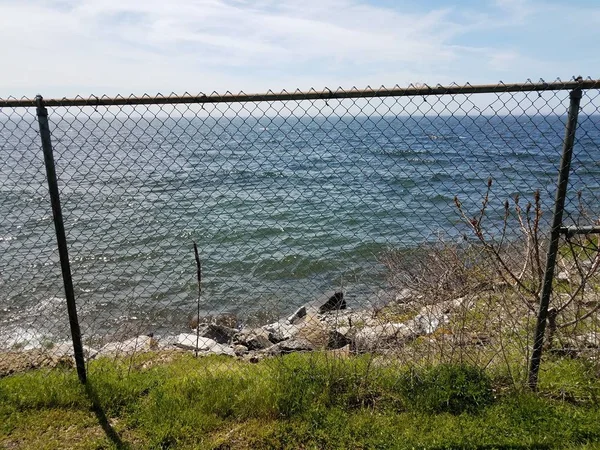 Μεταλλική αλυσίδα φράχτη σύνδεση με θαλασσινό ή θαλάσσιο νερό και γρασίδι — Φωτογραφία Αρχείου