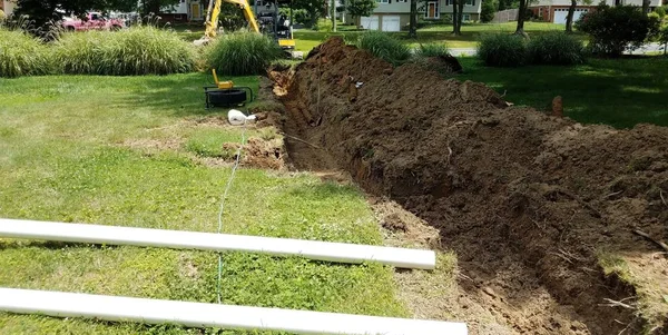 Sustitución de tuberías de alcantarillado con zanja y maquinaria en césped —  Fotos de Stock