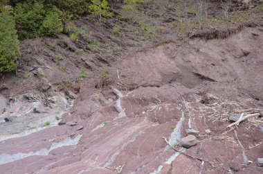 eğimli gri ve kırmızı kaya katmanları veya tepedeki tabakalar