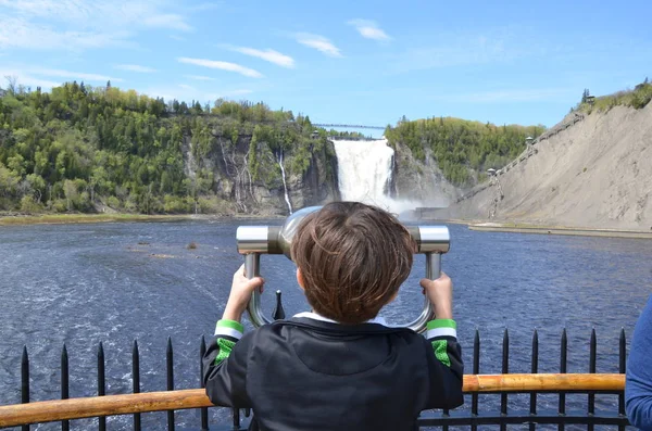 Мальчик ребенок смотрит через бинокль на водопад в Квебеке, Канада — стоковое фото