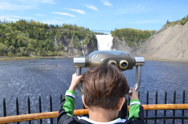 Мальчик ребенок смотрит через бинокль на водопад в Квебеке, Канада — стоковое фото