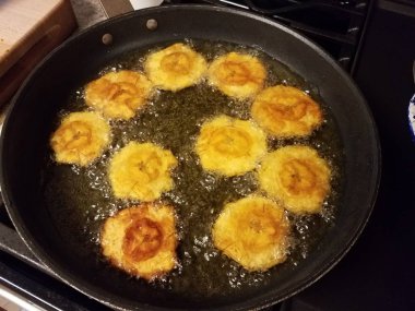 plantain bananas tostones Puerto Rican food cooking in oil in frying pan clipart