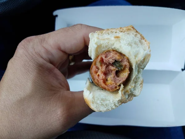 チーズとハラペーニョのホットドッグとパンを持つ手 — ストック写真
