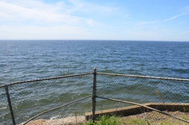 okyanus suyu ve gökyüzü ile metal zincir bağlantı çit