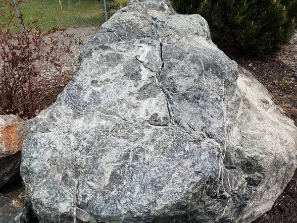 Piedra blanca grande o roca con venas y valla metálica — Foto de Stock