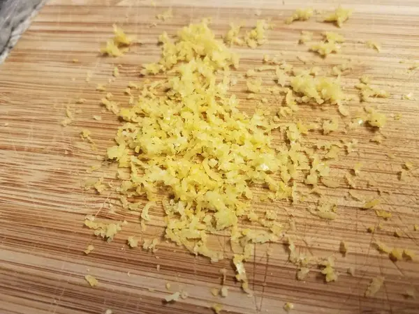 Wood cutting board with yellow lemon zest — Stock Photo, Image