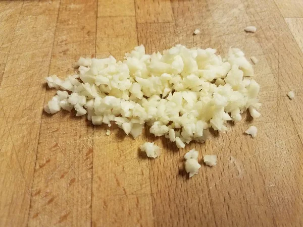 Wood cutting board with chopped garlic pieces — Stock Photo, Image