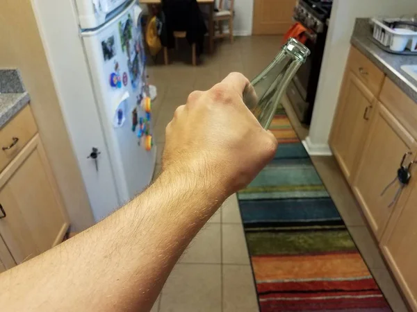 Mão segurando garrafa de bebida de vidro na cozinha — Fotografia de Stock