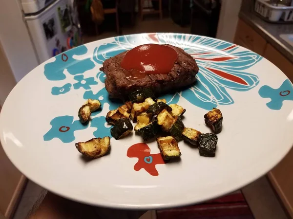 Assiette avec steak, ketchup et courgettes dans la cuisine — Photo