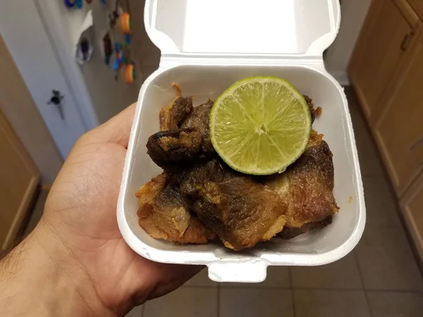 Hand holding container of fried pork with lime — Stock Photo, Image