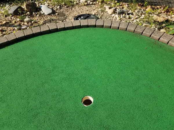 Último buraco em um campo de golfe em miniatura com tubo para balde de coleta de bola — Fotografia de Stock