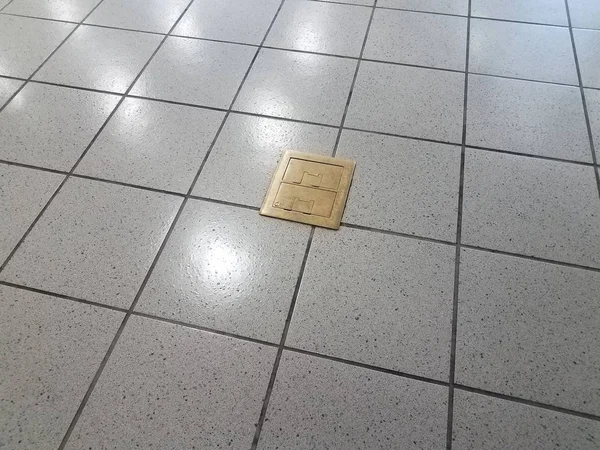 Brass metal electrical outlets on grey tile floor — Stock Photo, Image