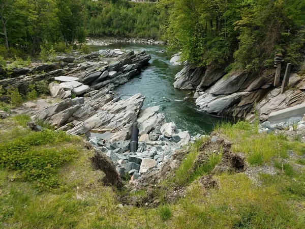 Зазубренные камни и вода в ручье или реке и трубе сброса — стоковое фото