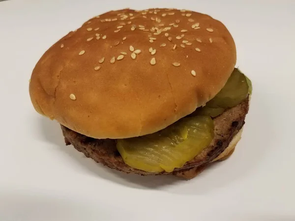 Hamburger with bun and pickle on white table — Stock Photo, Image