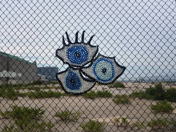 Fabric eyes on metal chain link fence at beach — Photo