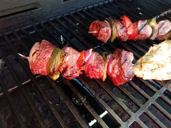 Carne de vaca kebob com cebolas e pimentas em um pau em uma grelha com frango — Fotografia de Stock
