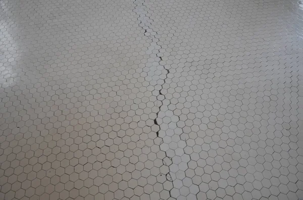 White hexagon floor tile with cracks or damage — ストック写真