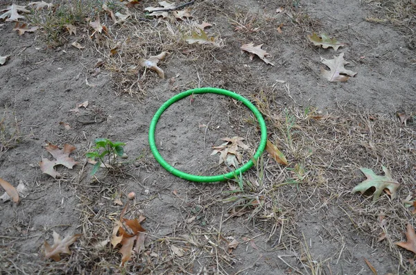 Anillo de plástico verde circular en hierba marrón o césped y suciedad — Foto de Stock