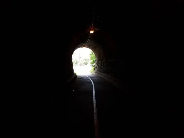 Tunnel with stone wall and light at end of tunnel — Stock Fotó